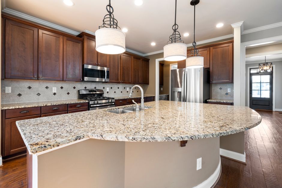 Spacious kitchen featuring a granite island, dark wood cabinets, and stainless steel appliances.